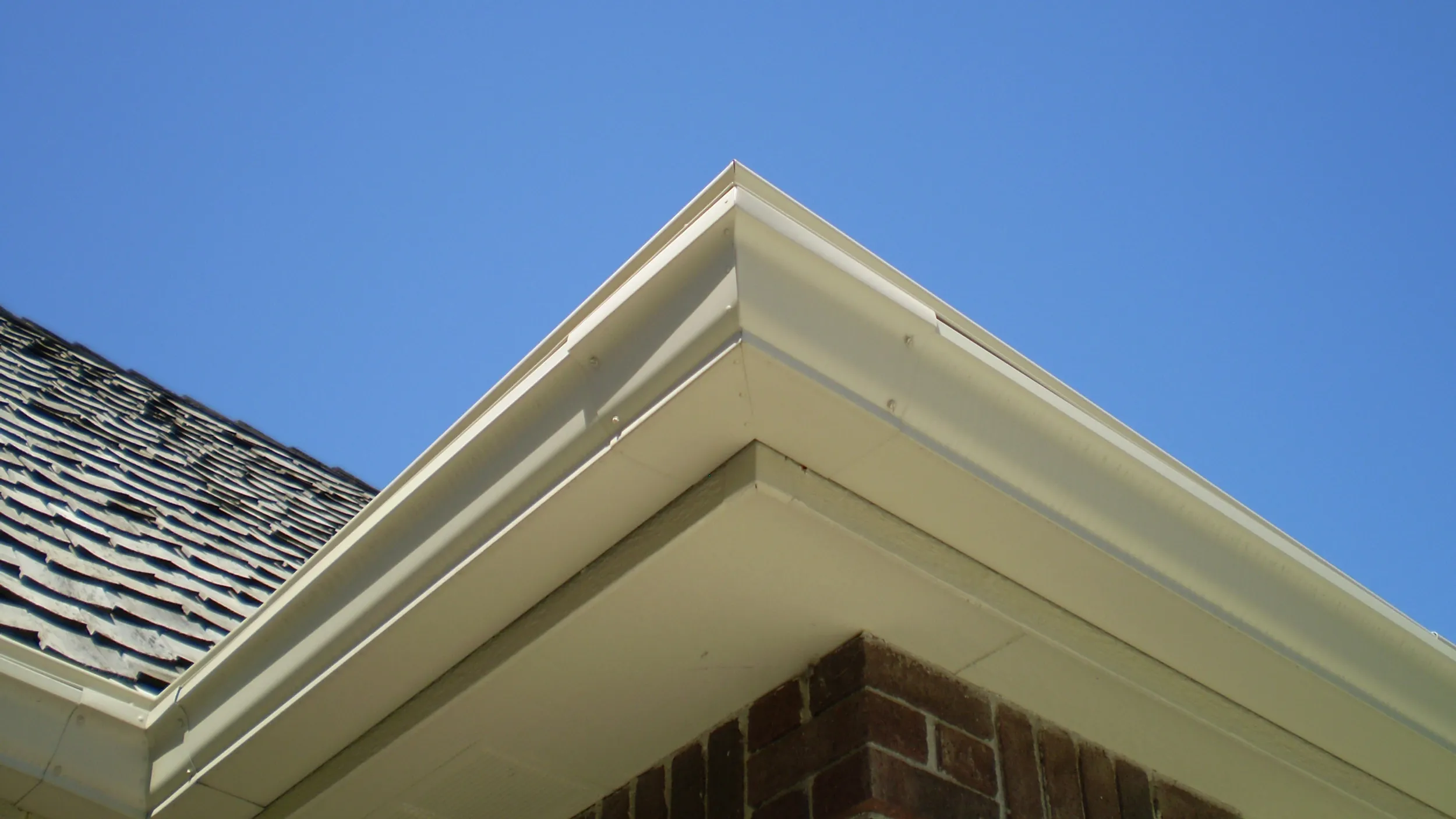 LeaFree on a gutter seen from the yard below: a clean roofline, the hood tucked under the shingles.